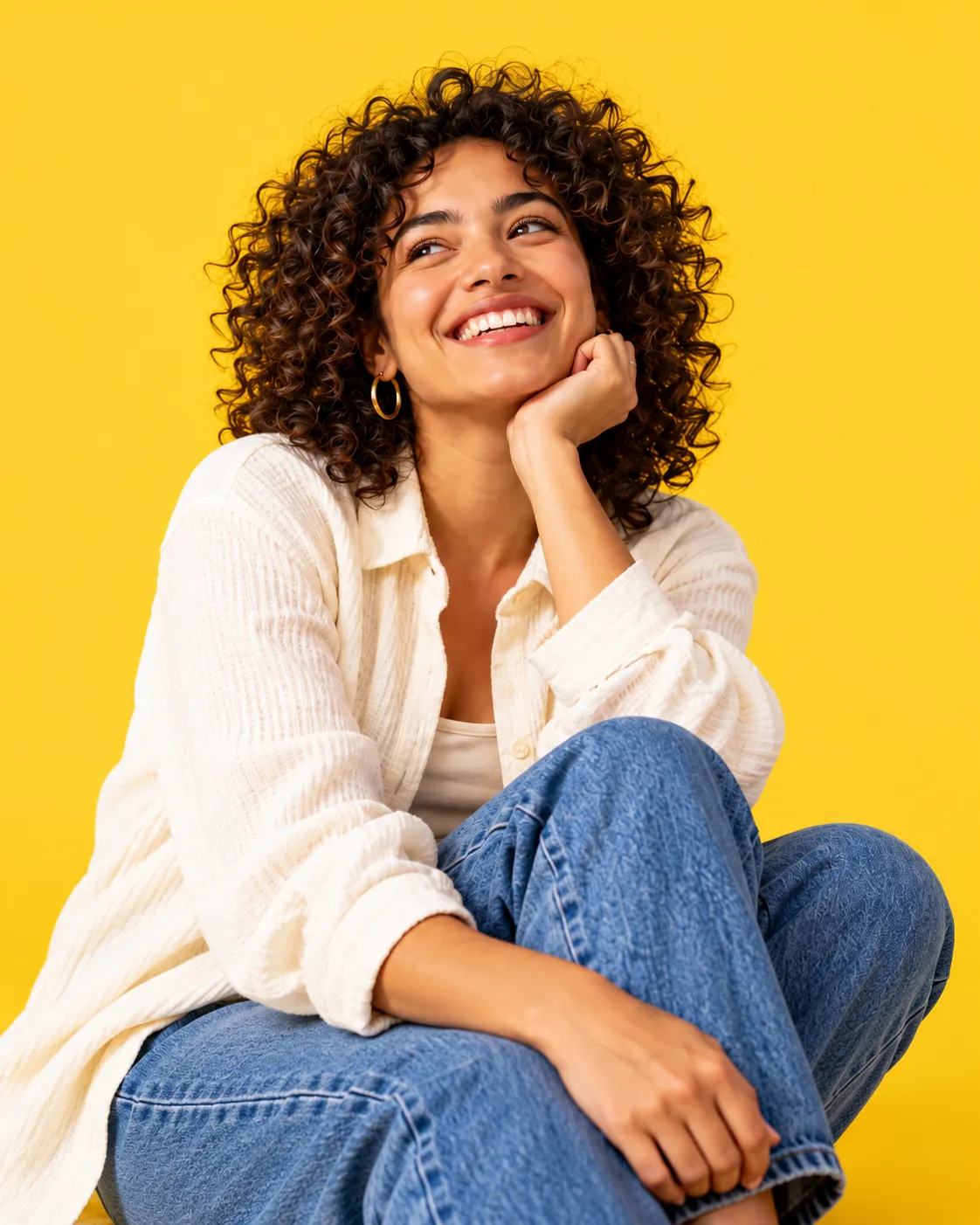 Woman with curly hair smiling, chin on her hand